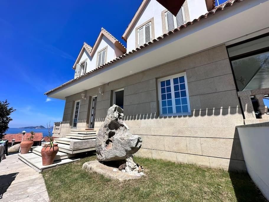 Casa de piedra con tres buhardillas, cielo azul, escultura en el patio, cerca de la costa.