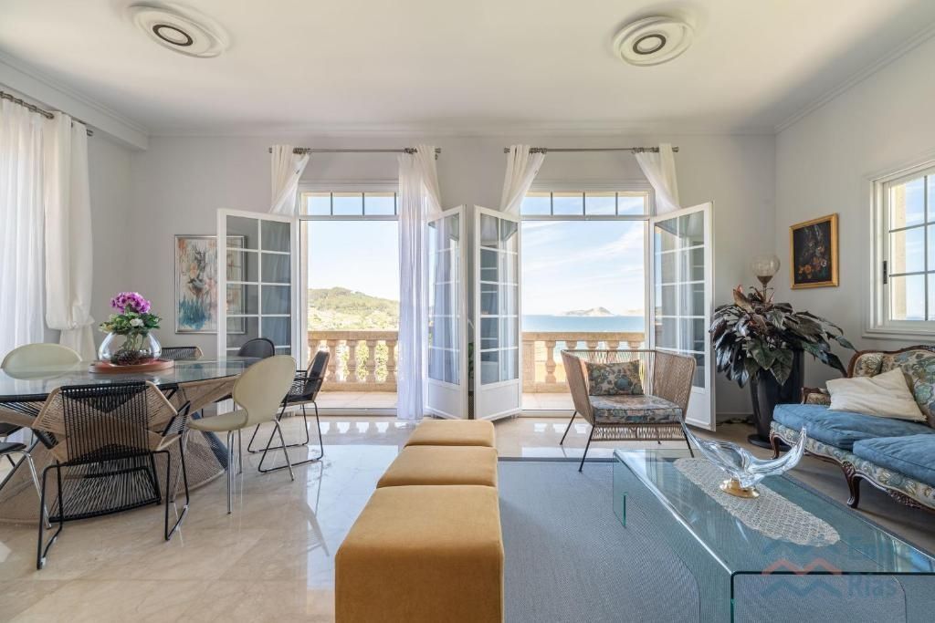 Amplia sala de estar con vista al mar, puertas francesas y muebles estampados.