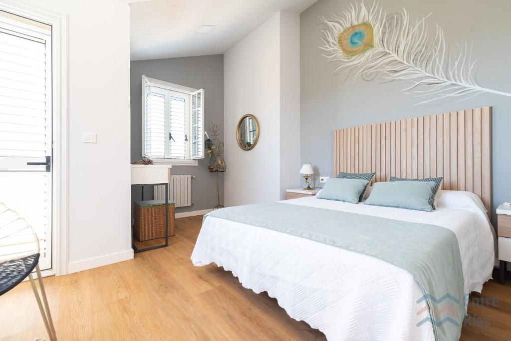 Dormitorio con cama blanca, cabecero de madera y diseño de plumas de pavo real en la pared.