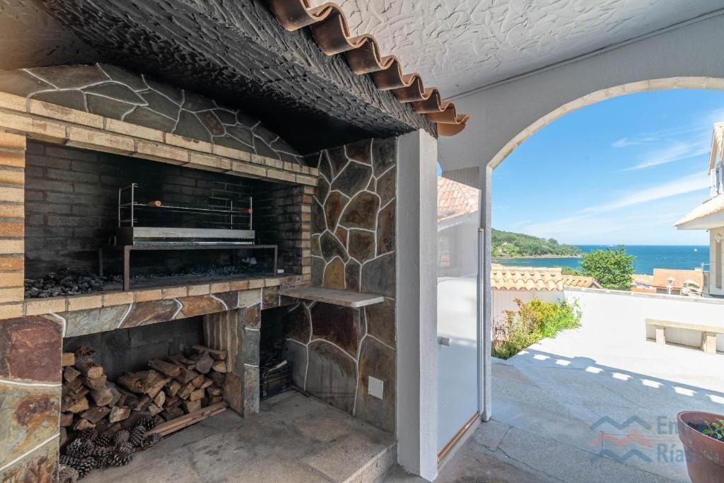 Barbacoa de piedra al aire libre con vista al mar a través de un arco.