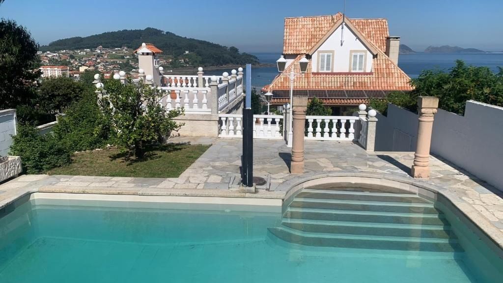 Piscina frente a casa con techo de tejas, con vistas a un paisaje costero.