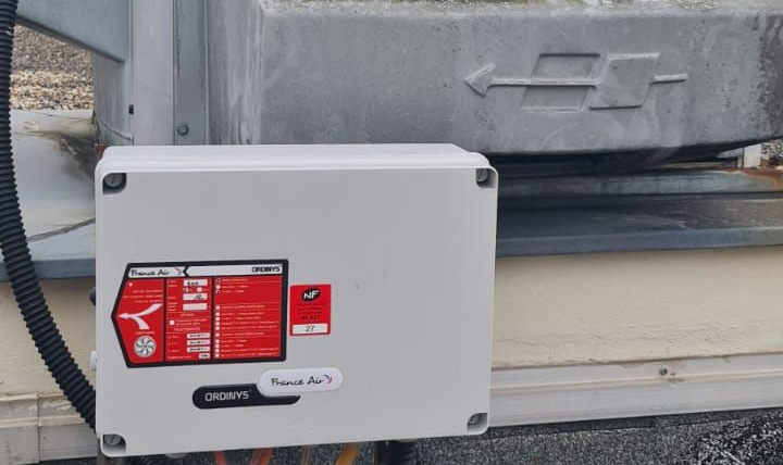 Toiture métallique avec deux puits de lumière. Ciel dégagé en arrière-plan.