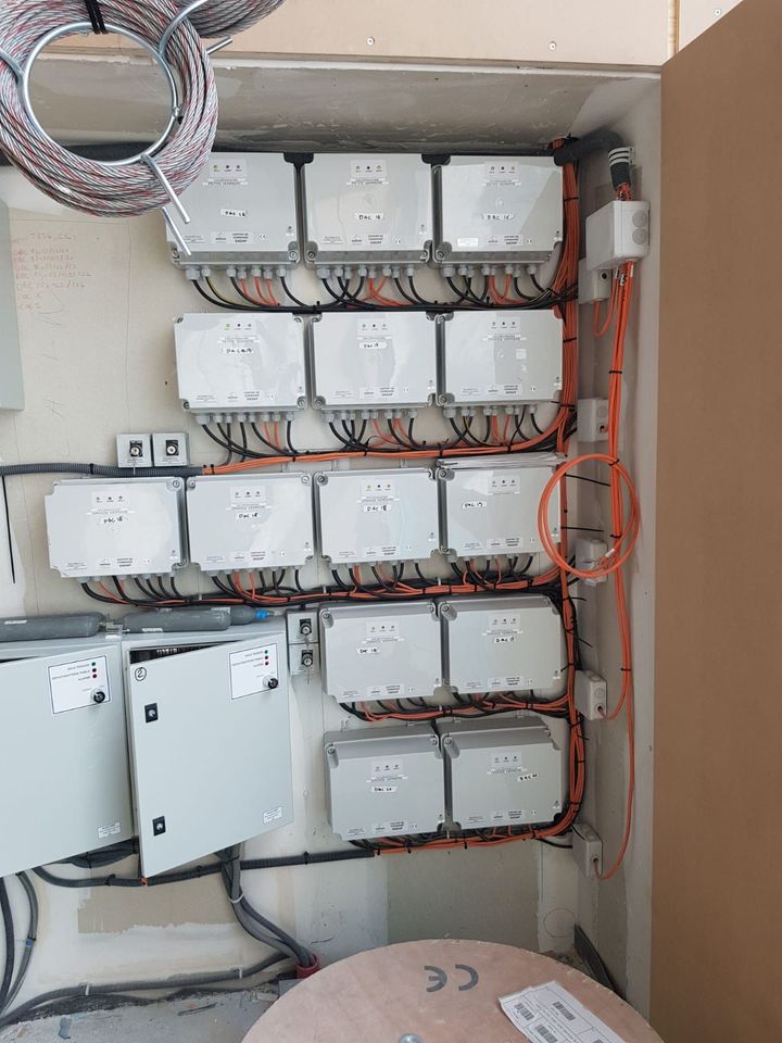 Boîtes électriques murales avec câblage orange, câbles et conduits dans un placard utilitaire.