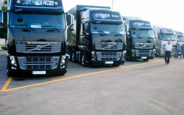 Una fila de semirremolques Volvo están estacionados en un estacionamiento.