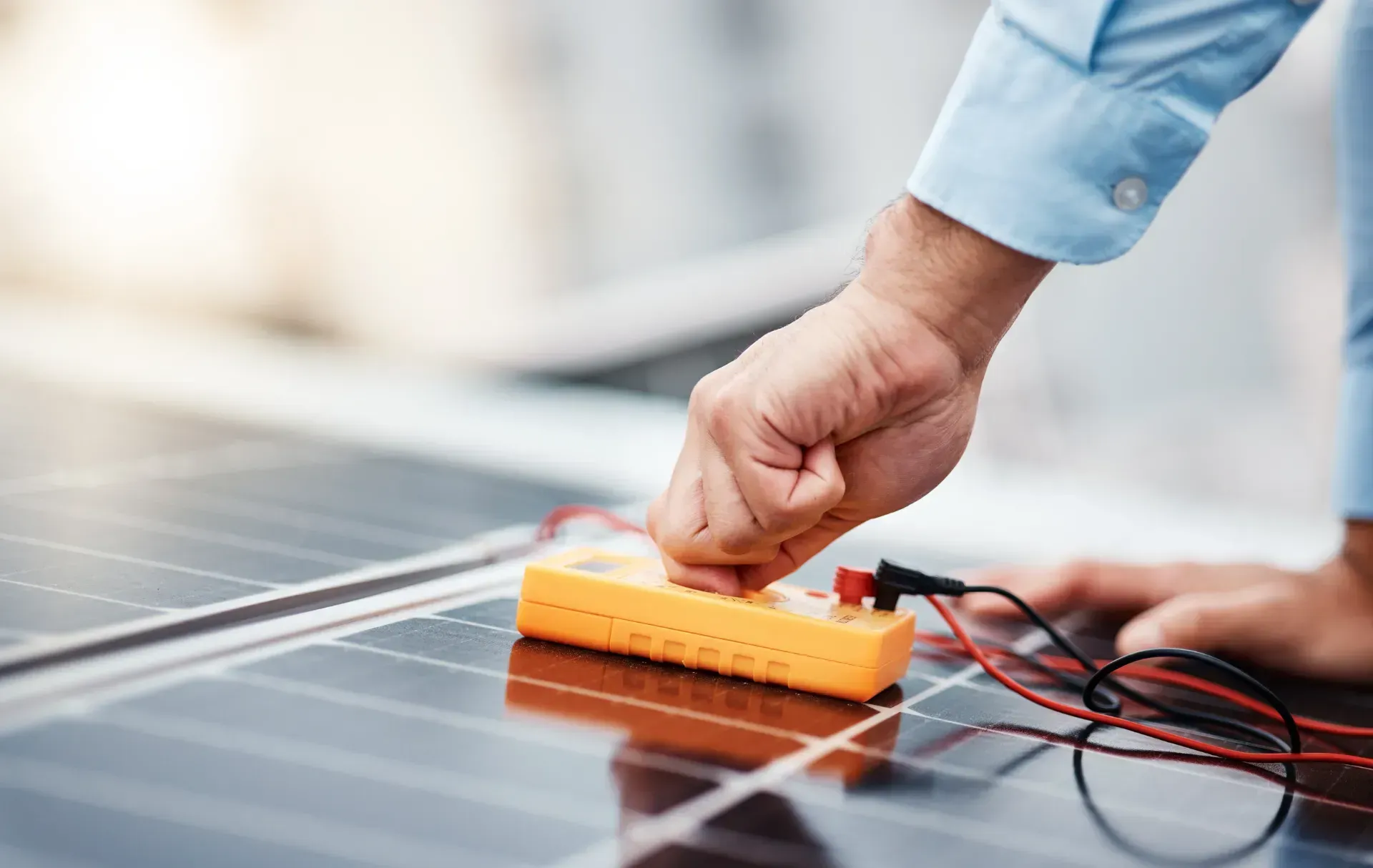 Un hombre está usando un multímetro para probar un panel solar.