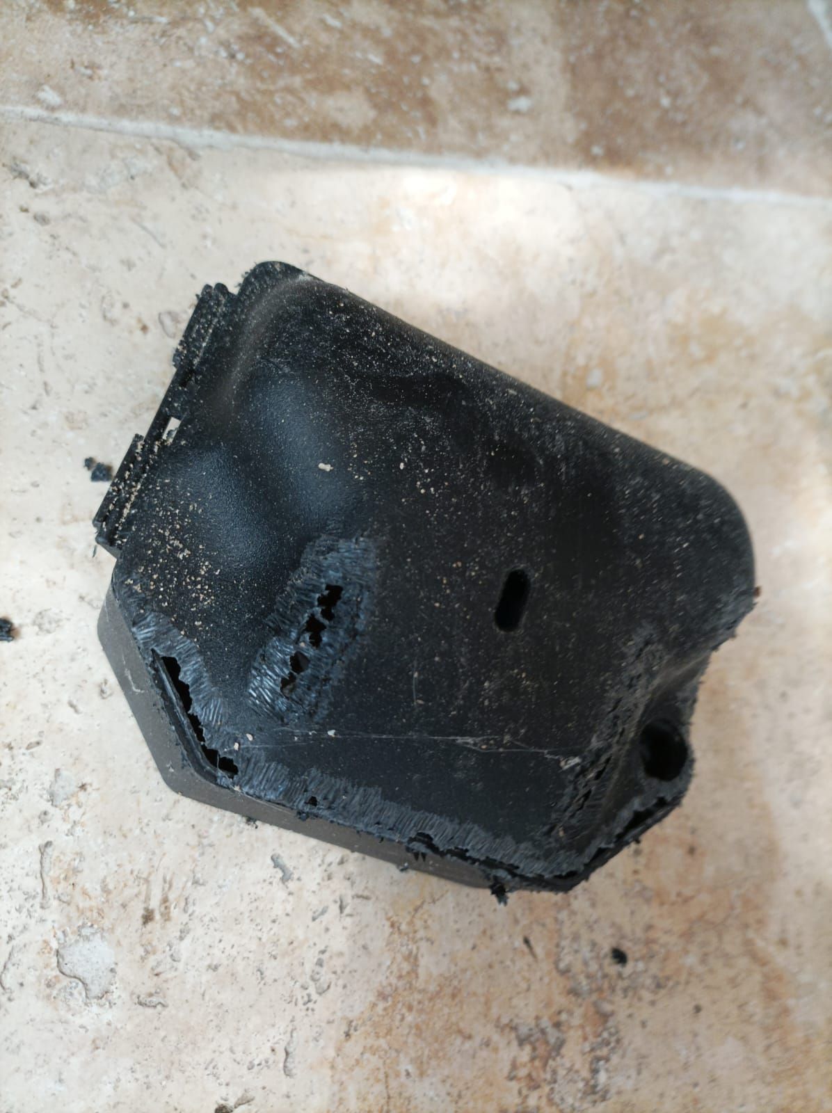 Un objet noir est posé sur un sol carrelé.