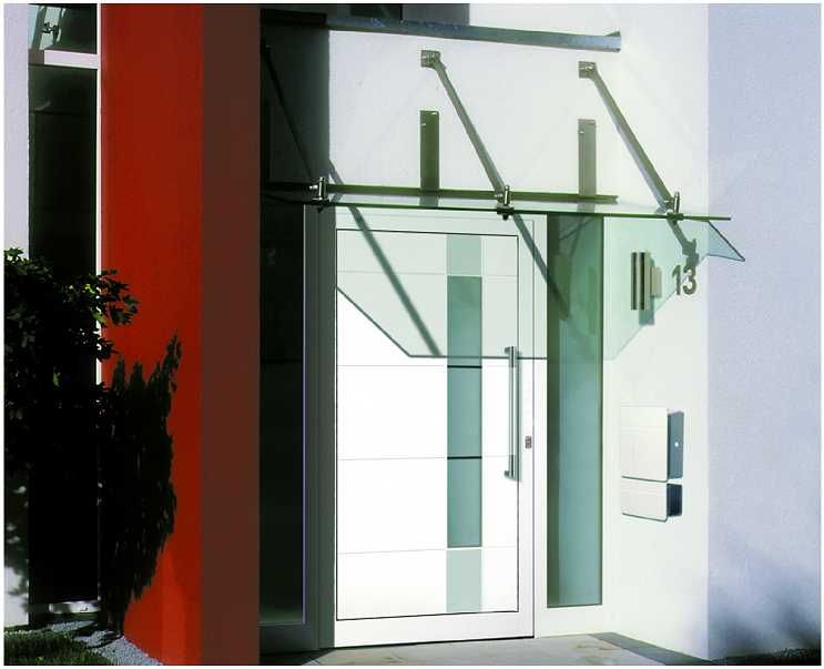 Moderne Eingangstür aus Glas und Metall mit Glasvordach vor weißen und roten Wänden.