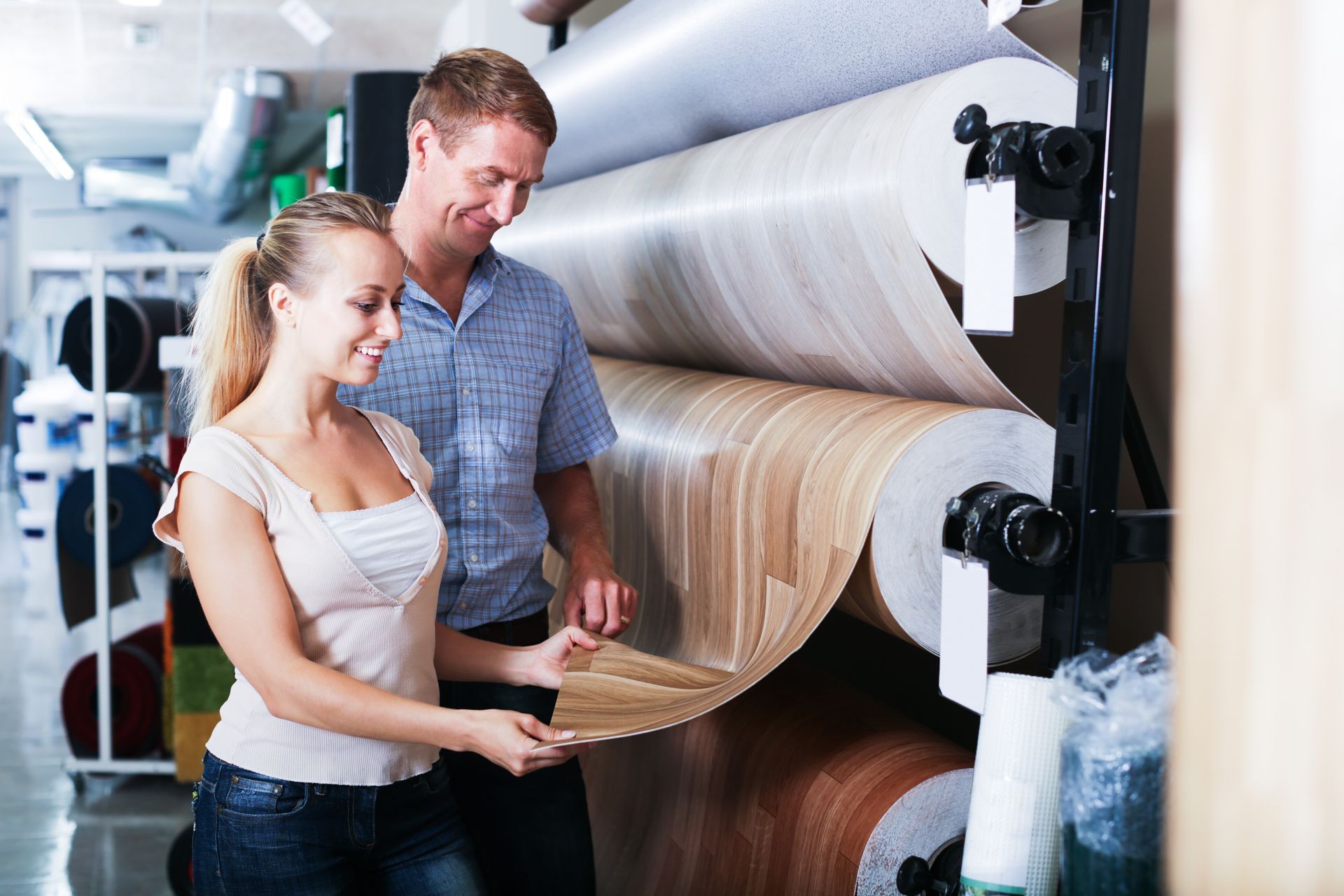 Un couple regarde différents rouleaux de linoléum