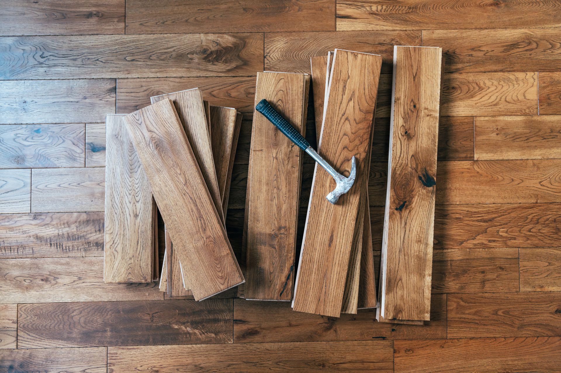 Pile de lames de parquet massif avec un marteau dessus