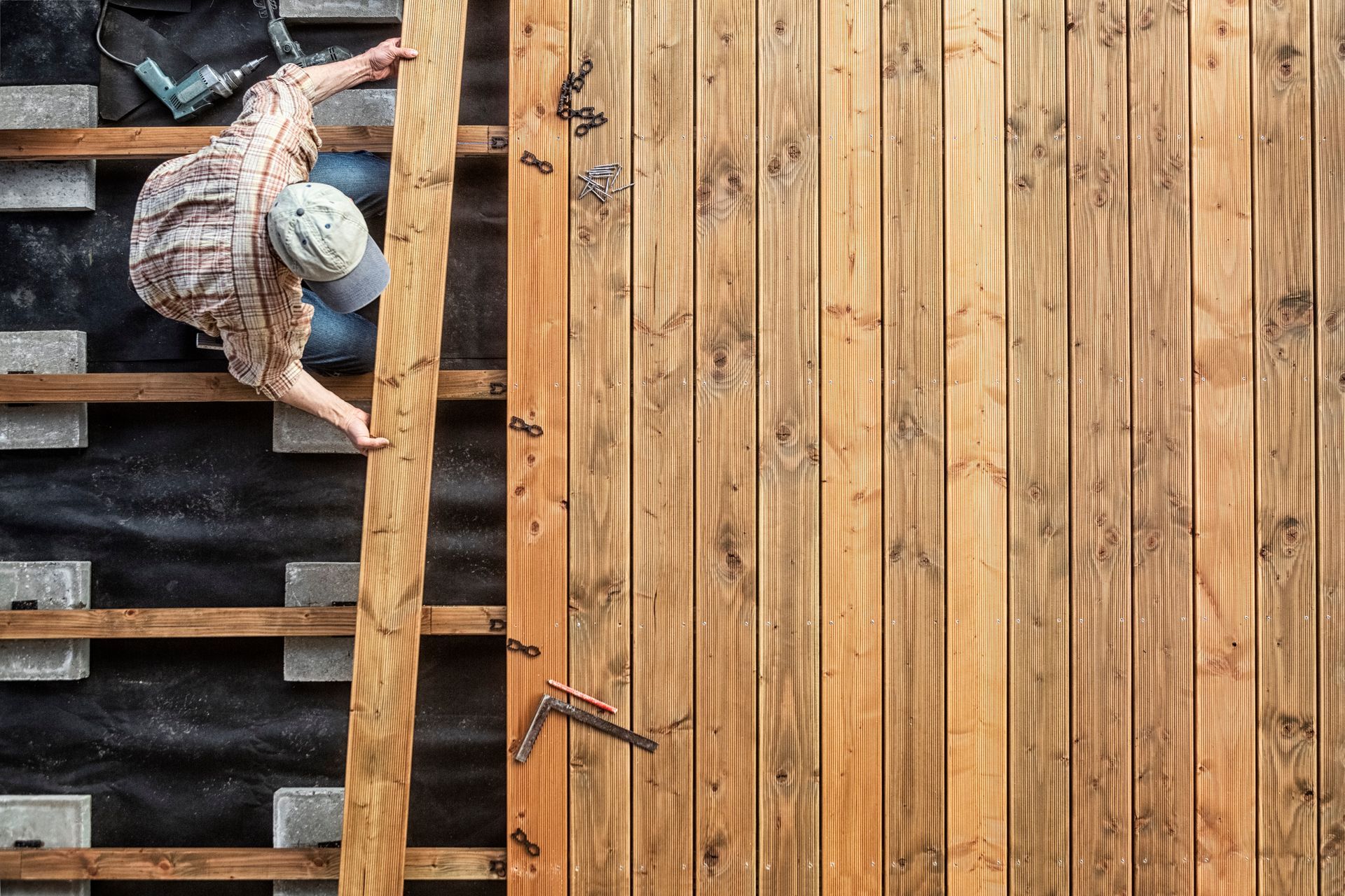 Un homme pose les lames de bois d'une terrasse