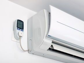 Um ar condicionado branco está pendurado em uma parede branca.
