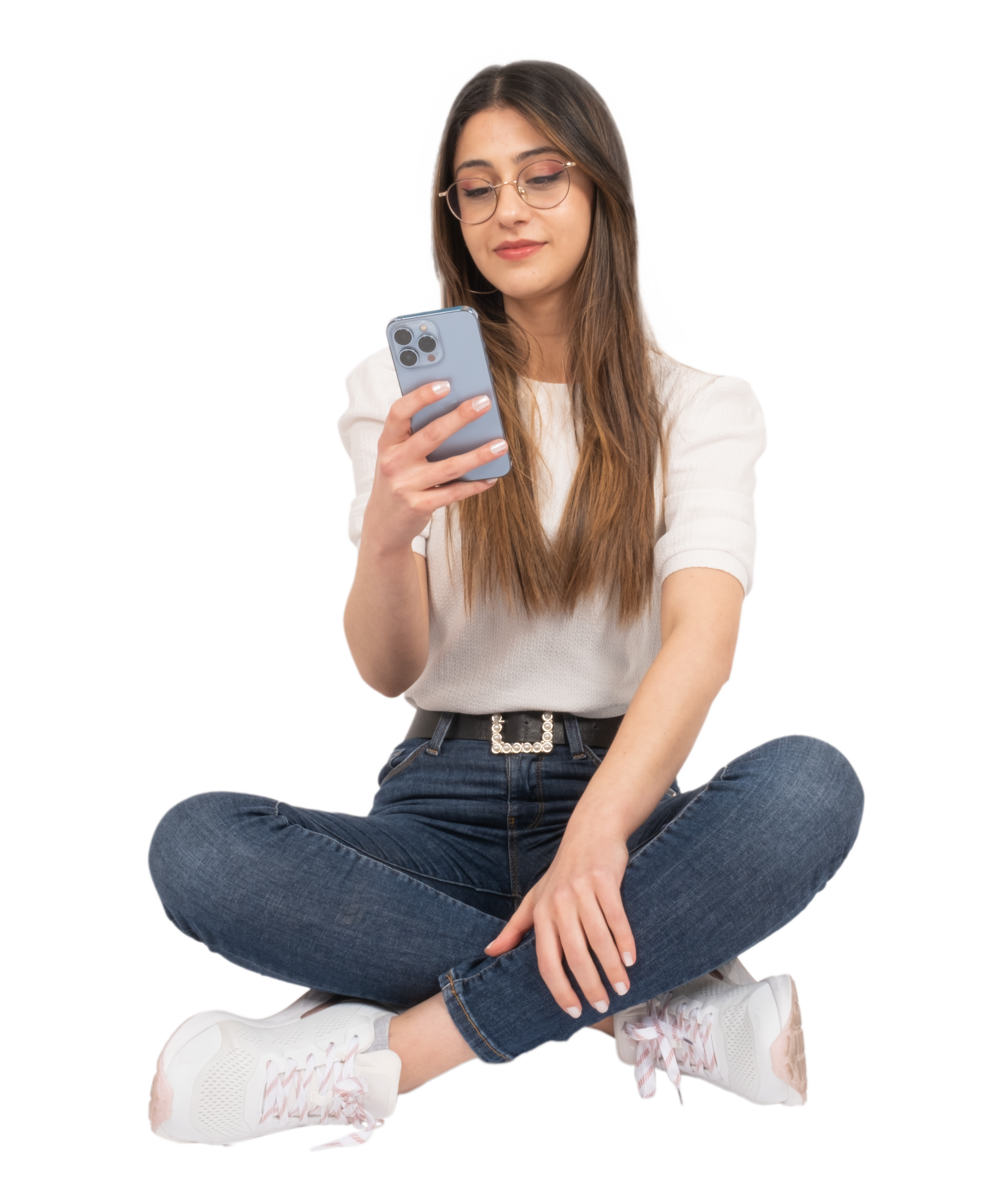 Personne assise en tailleur, regardant un smartphone, portant des lunettes, une chemise, un jean et des baskets.