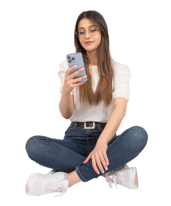 Personne assise en tailleur, regardant un smartphone, portant des lunettes, une chemise, un jean et des baskets.