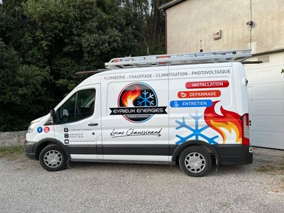 Une camionnette de service ornée de motifs de flammes colorées et de logos d'entreprises est garée à l'extérieur, près d'un bâtiment.