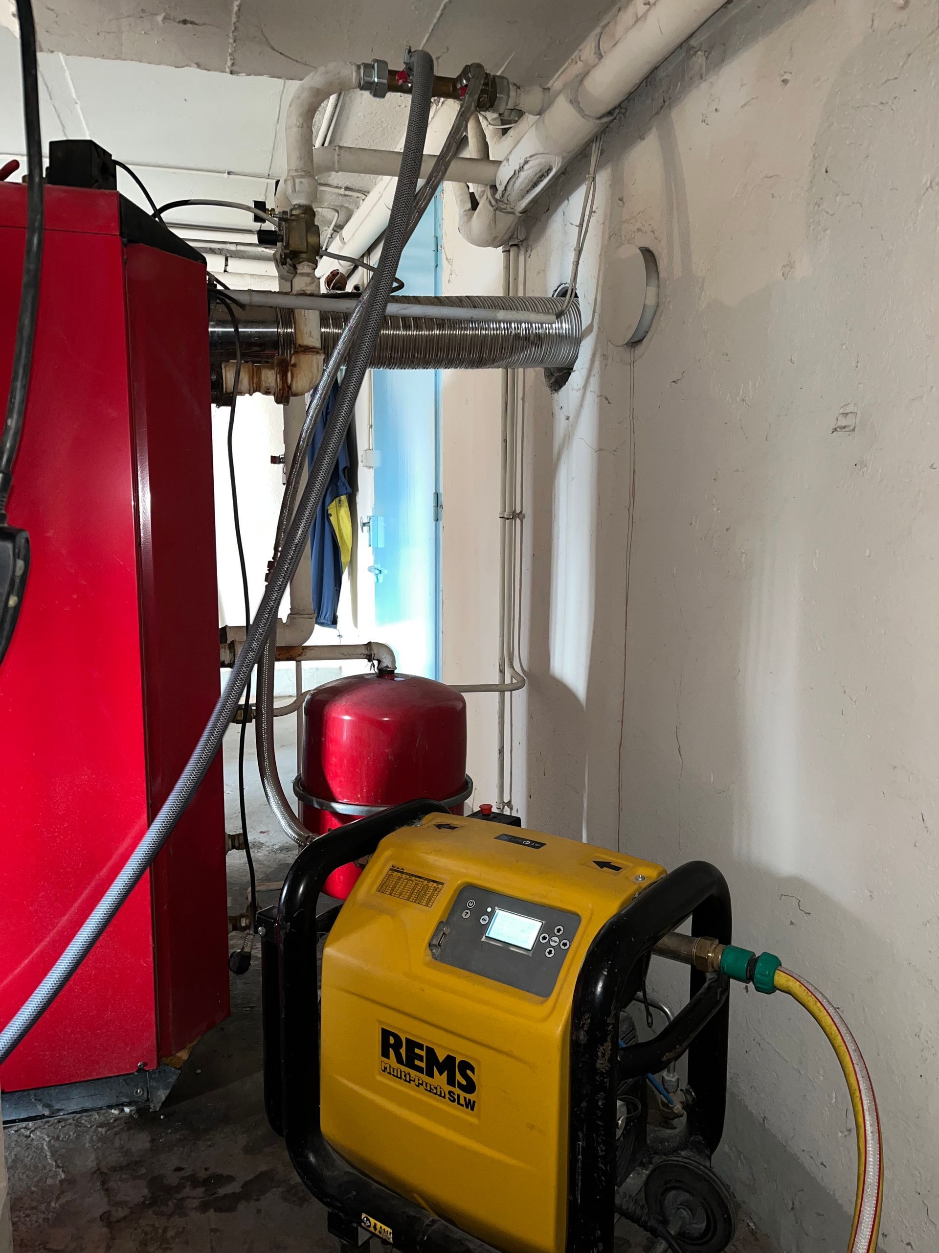 Machine REMS à côté du réservoir et des tuyaux dans une petite buanderie.
