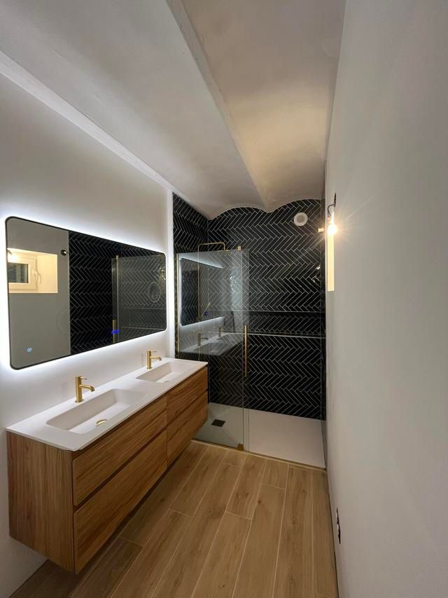 Salle de bains moderne avec un meuble de lavabo en bois, un lavabo,  un miroir et douche carrelée.