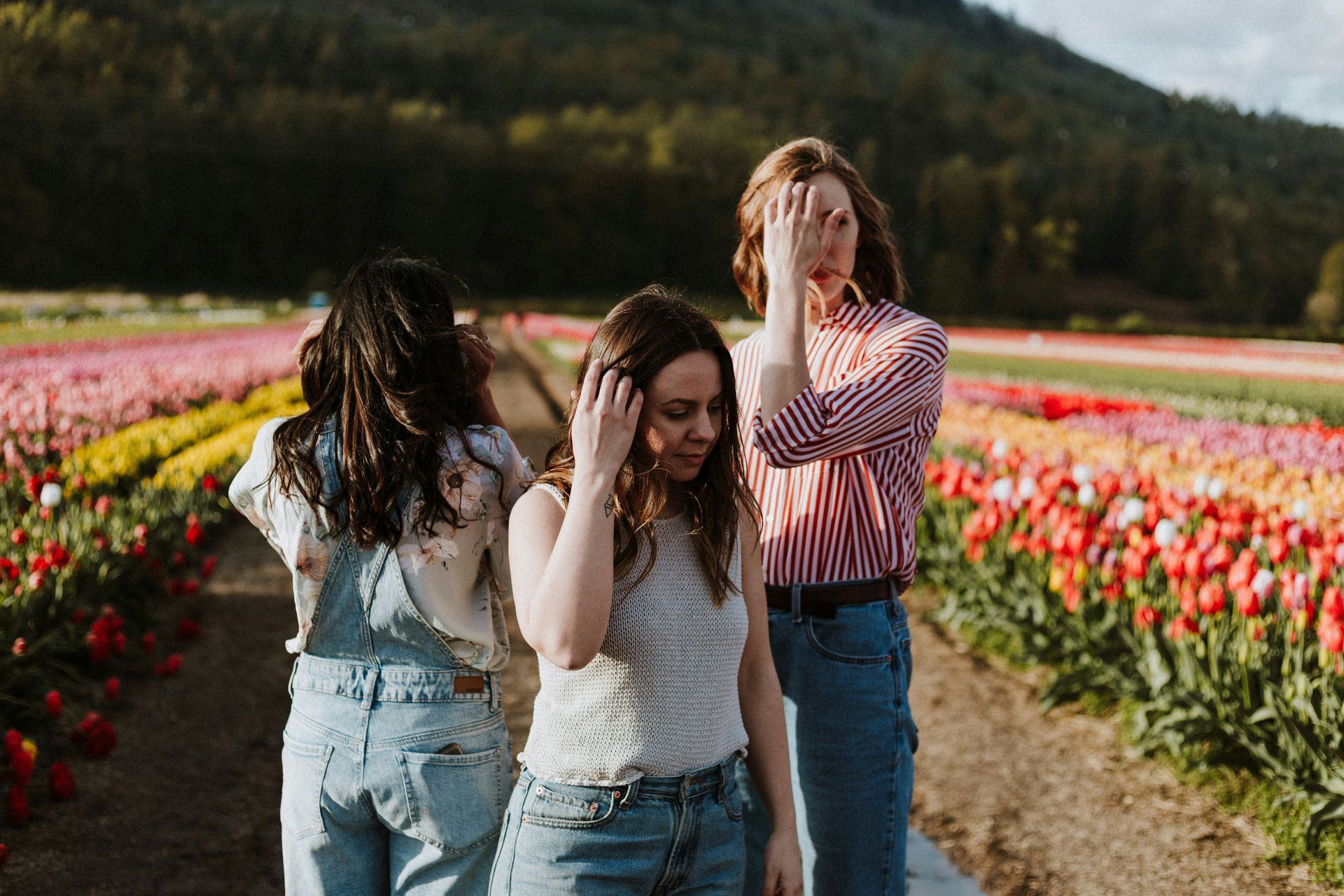 Tres personas paseando por un colorido campo de flores en un día soleado.