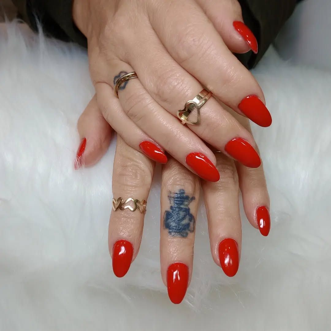 Un primer plano de las manos de una mujer con uñas rojas y anillos.