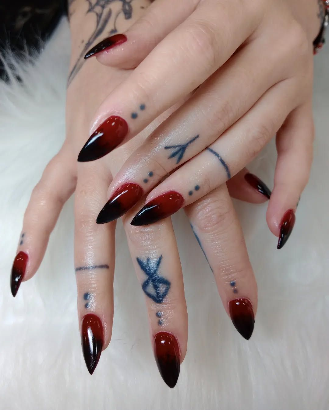 Un primer plano de las manos de una mujer con uñas rojas y negras.