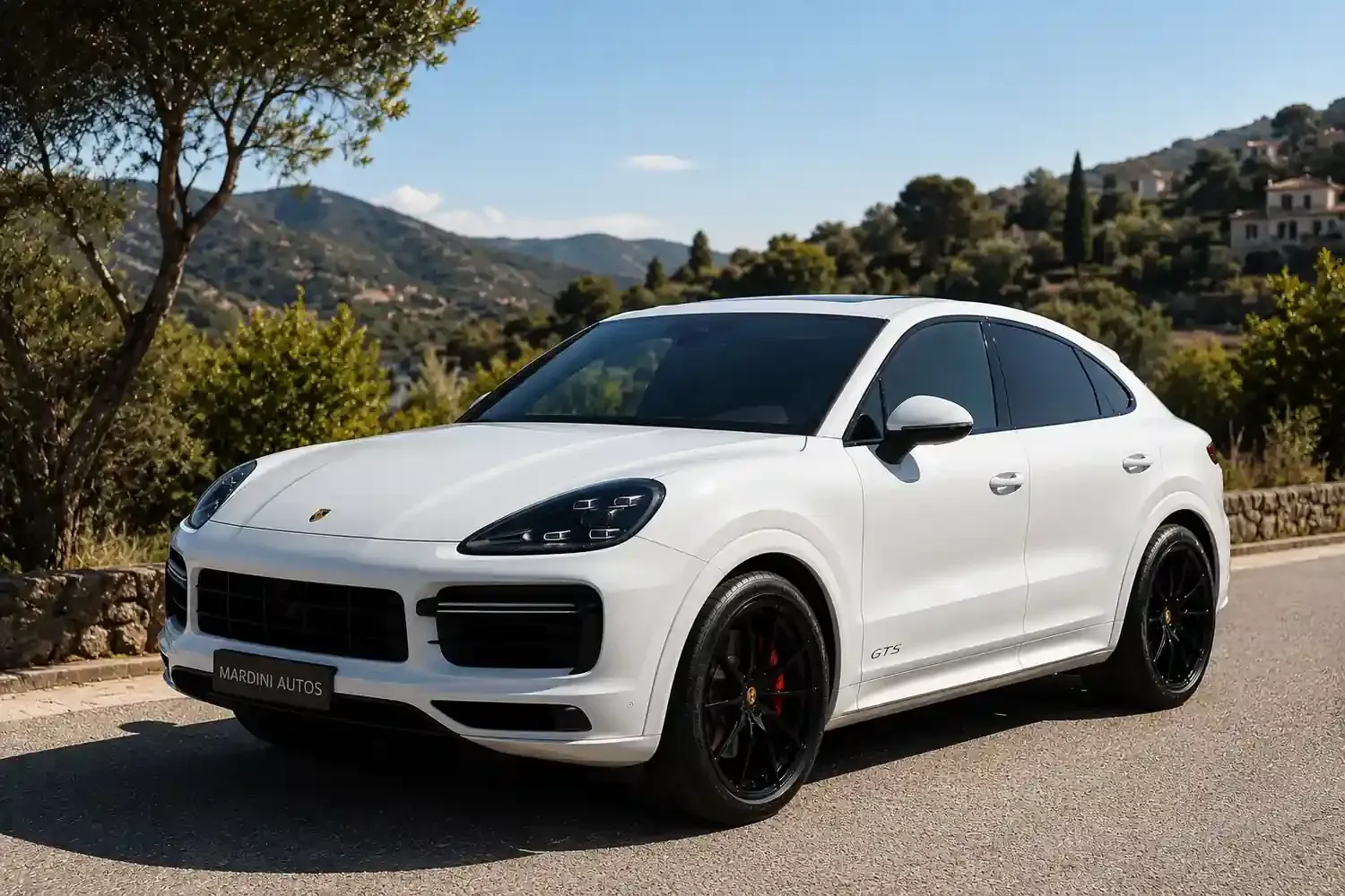 SUV Porsche blanco estacionado en una carretera con colinas y árboles al fondo.