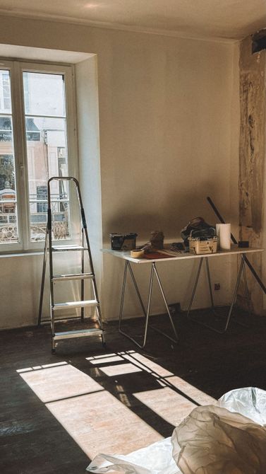 Pièce baignée de soleil avec une échelle près de la fenêtre et une table sur laquelle sont posés outils et fournitures.