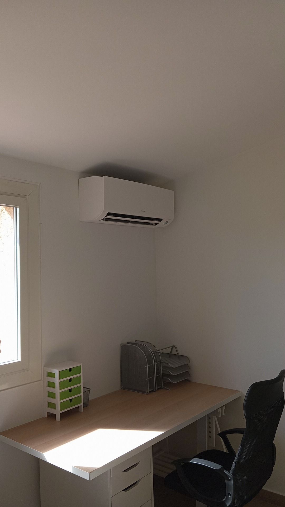 Bureau avec bureau, chaise et climatiseur sur mur blanc.
