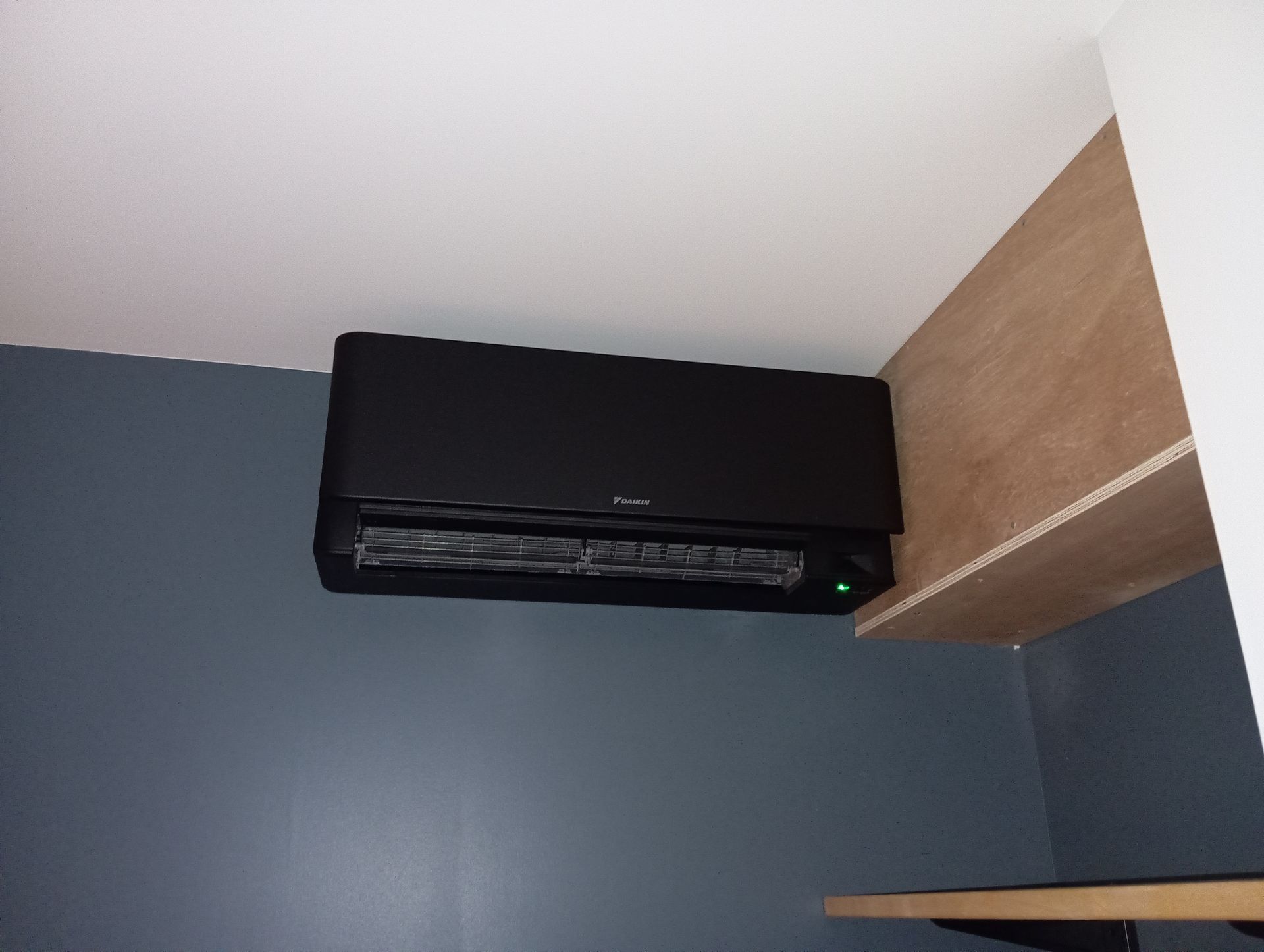 Unité de climatisation noire sur un mur bleu