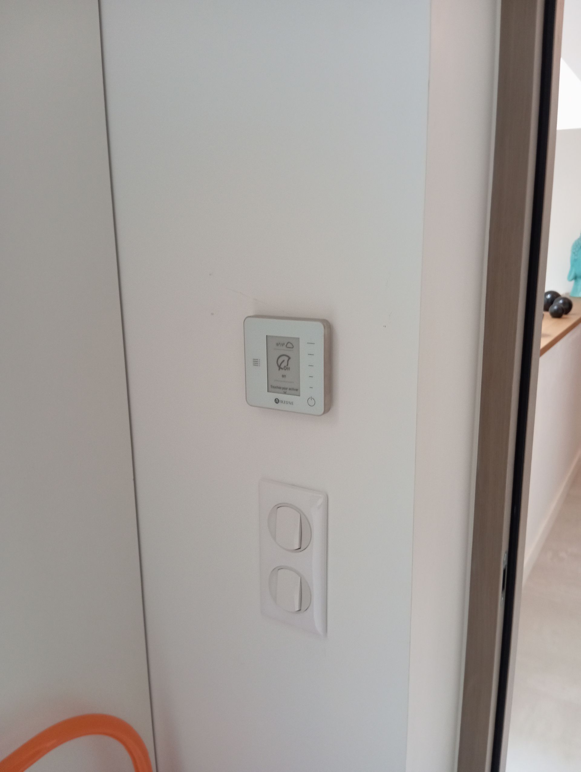Mur blanc avec un thermostat et un interrupteur.