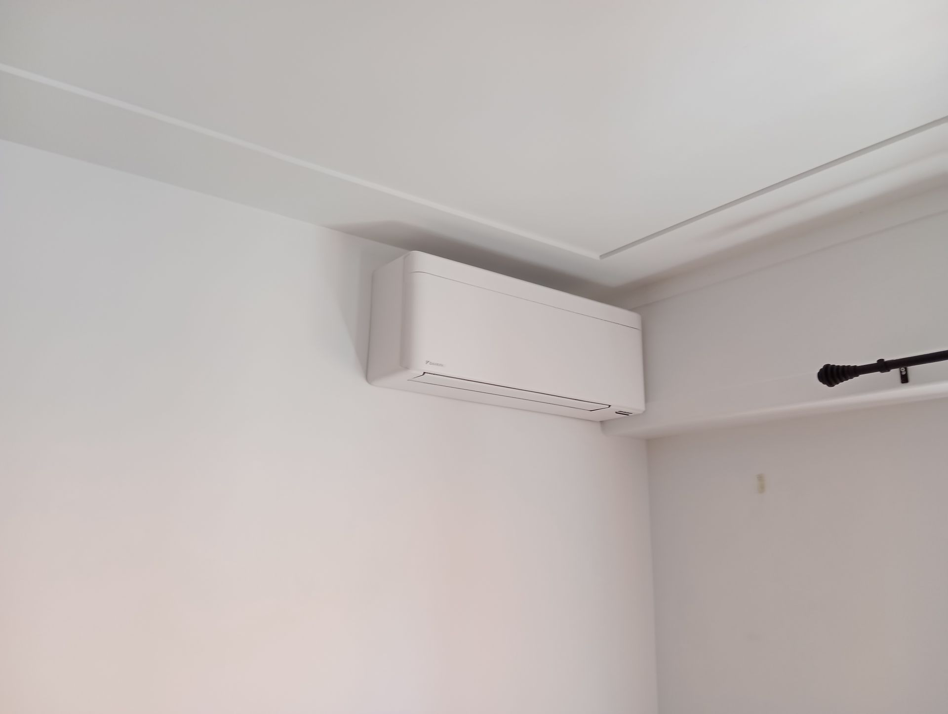 Climatiseur blanc sur un mur blanc dans un coin d'une pièce.