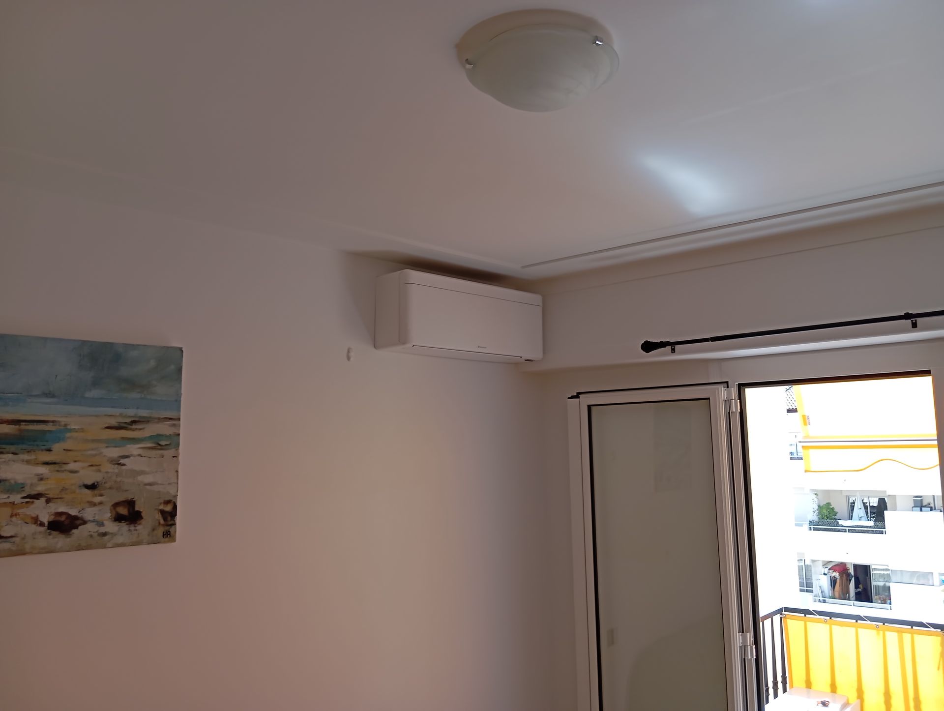 Intérieur d'une pièce avec climatisation, œuvres d'art et porte-fenêtre.