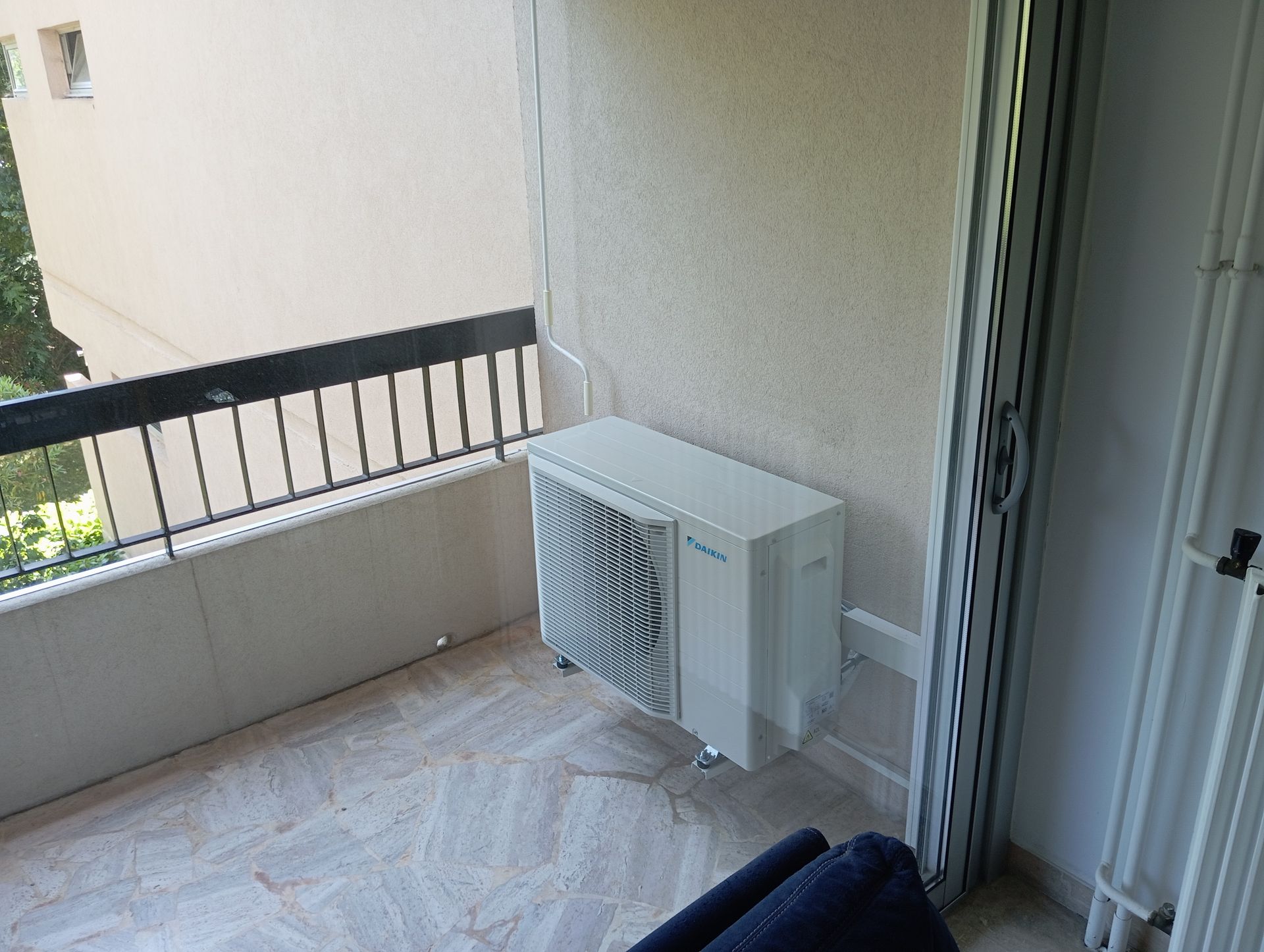 Unité de climatisation sur un balcon avec une balustrade noire.