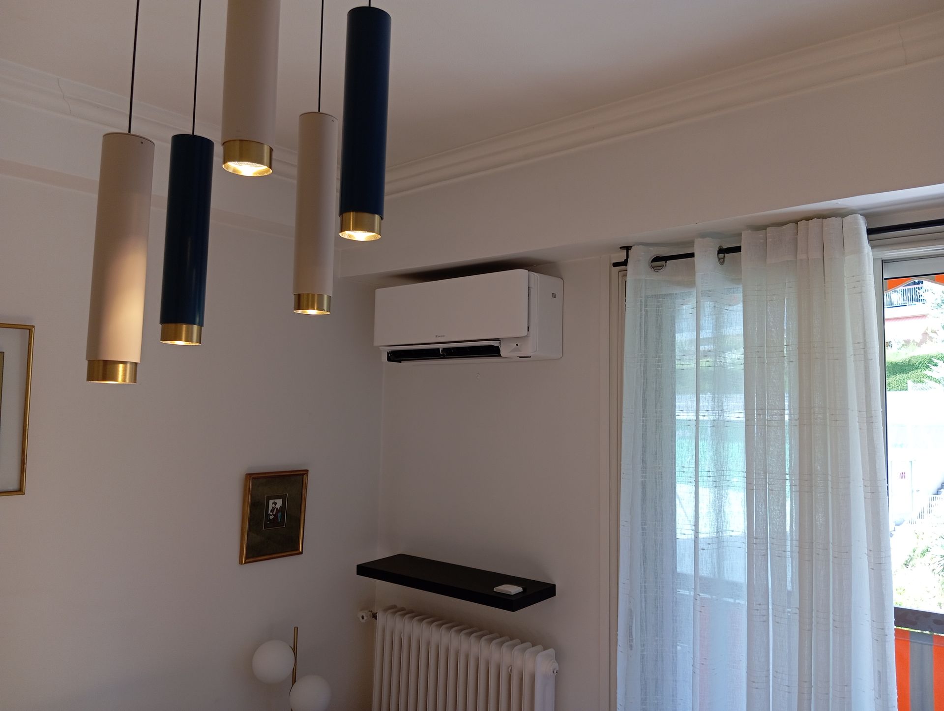 Intérieur de la pièce avec murs blancs, climatiseur, radiateur, rideaux et suspensions.
