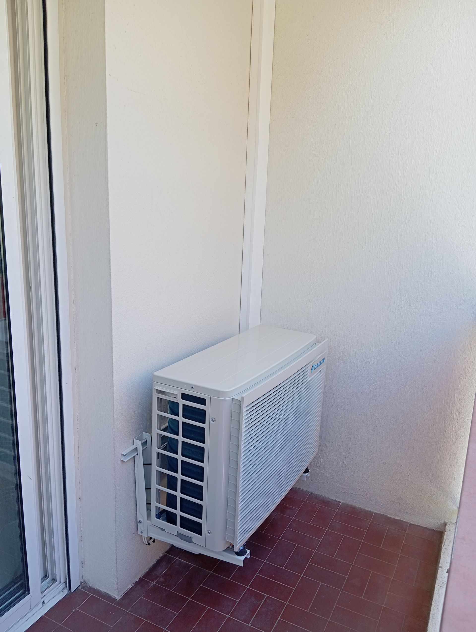 Unité de climatisation blanche montée sur un mur extérieur.