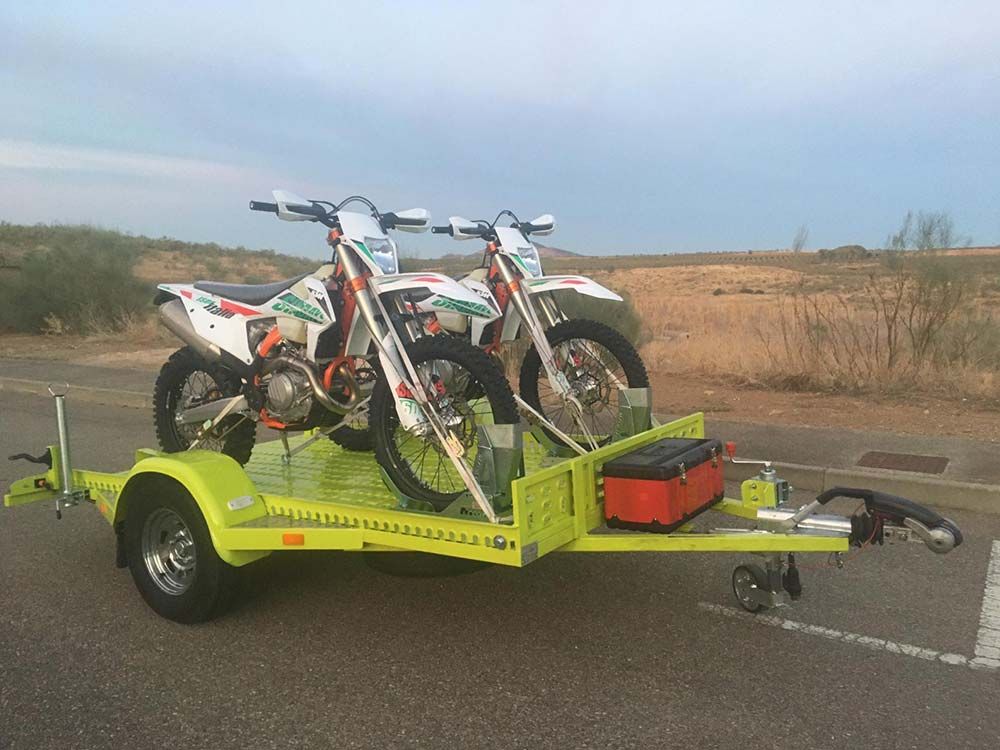 Dos motos de cross están sentadas encima de un remolque.
