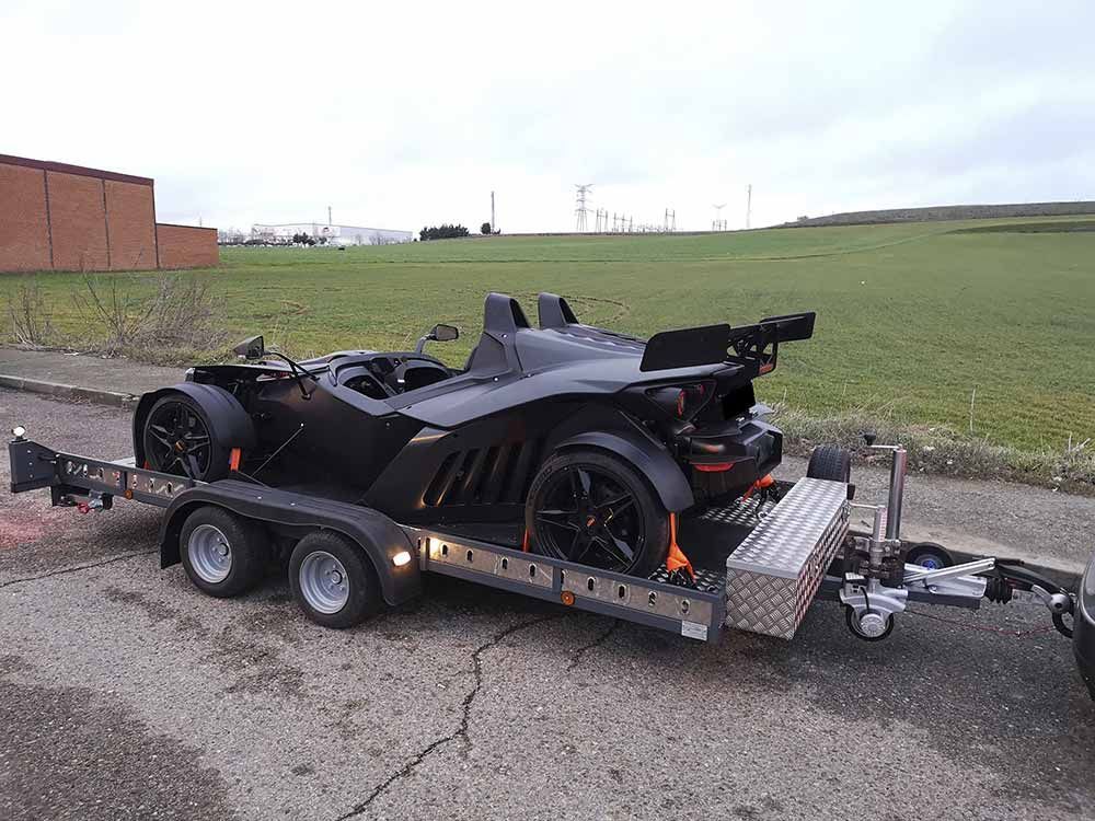 Un coche deportivo negro está siendo remolcado por un remolque.