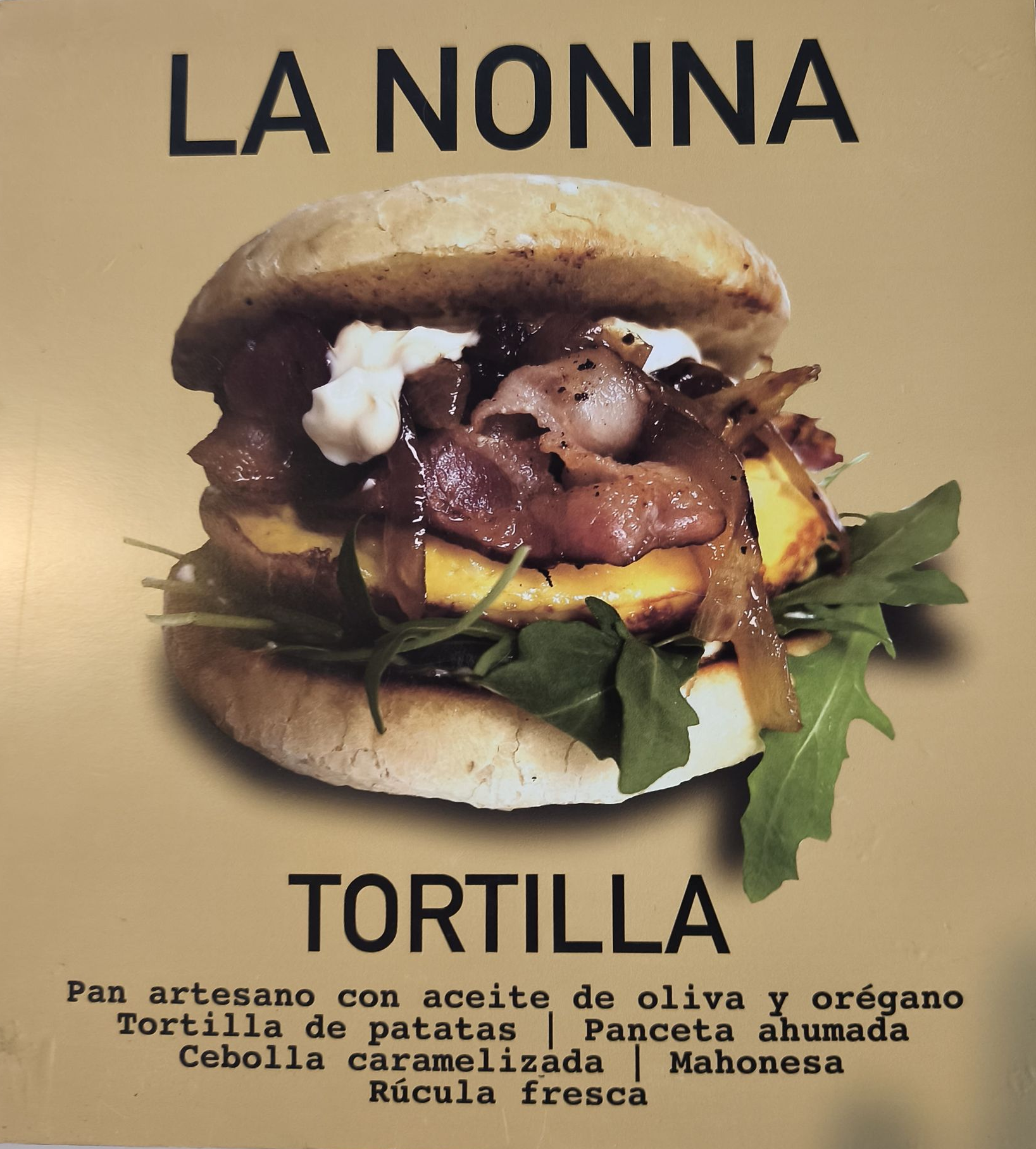 Sándwich con tortilla, panceta, cebolla caramelizada y rúcula, etiquetado 