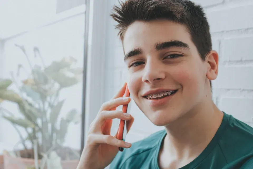 Joven sonriente con el teléfono pegado a la oreja en una habitación luminosa.