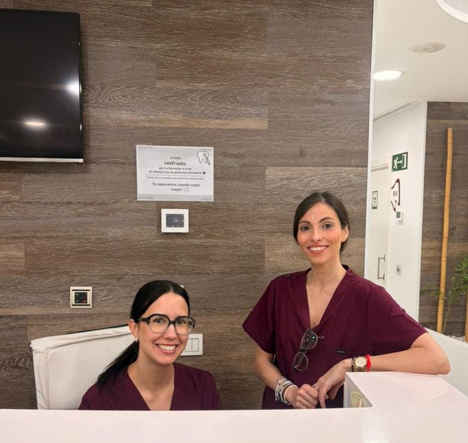 Higienista dental hablando con un paciente en el sillón dental durante una revisión.