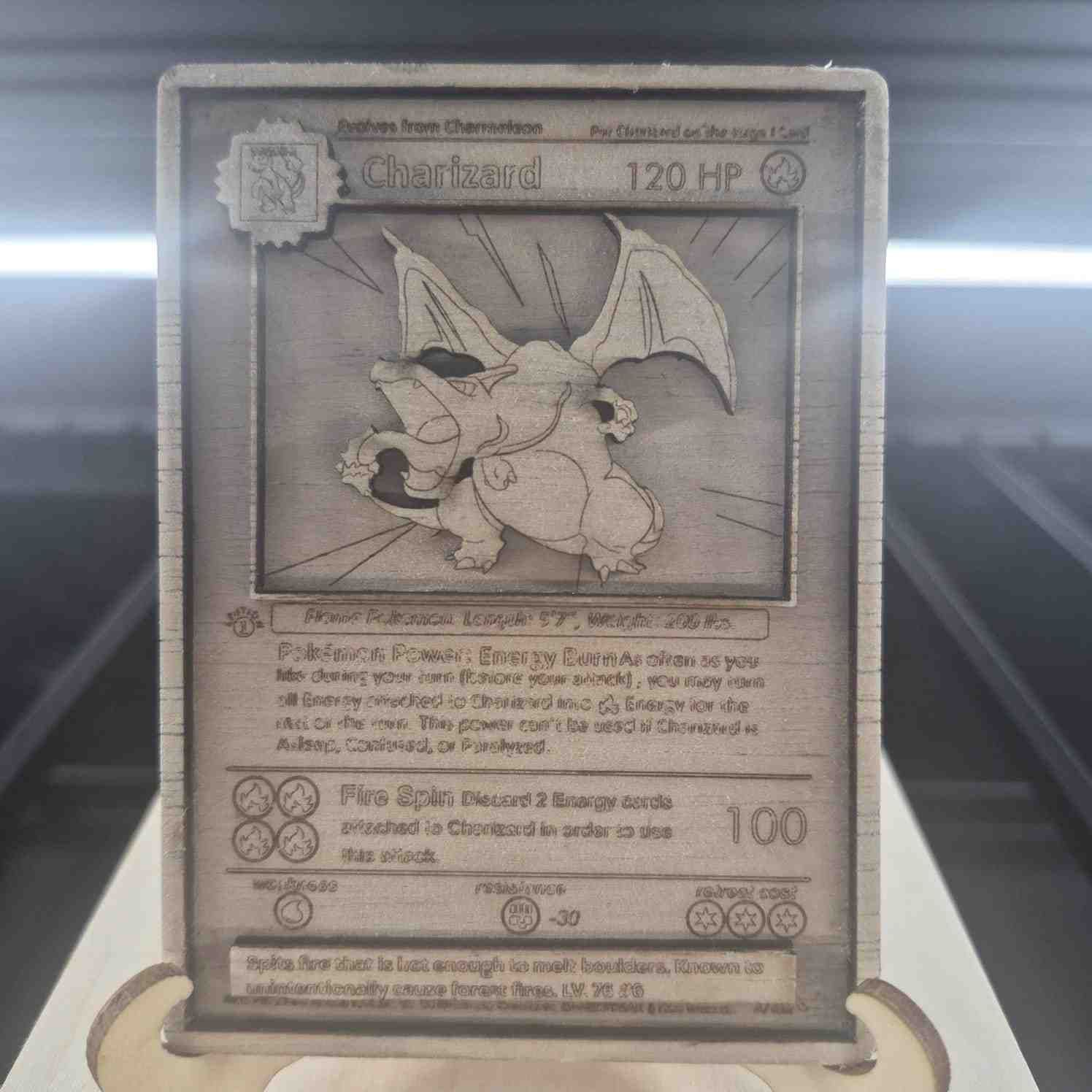 Tarjeta Pokémon de Charizard de madera grabada con láser. Representa a la criatura con detalles del diseño original.
