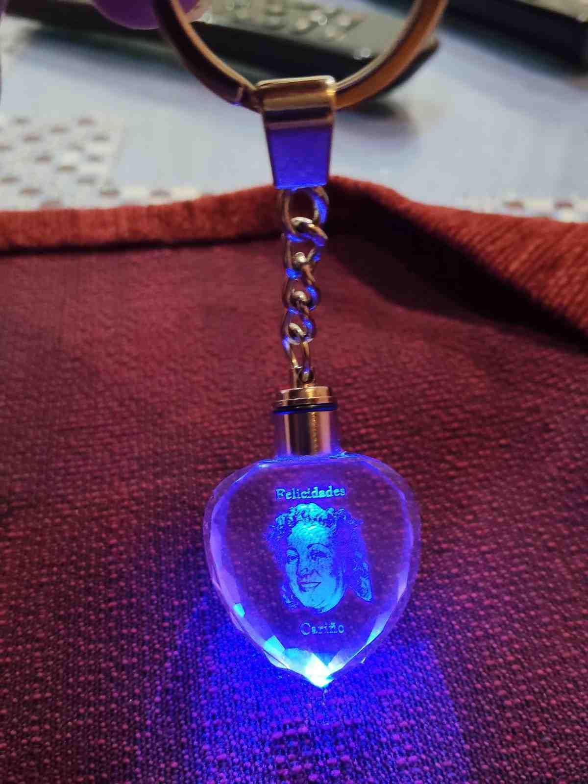 Llavero azul brillante con forma de corazón y un retrato de mujer en su interior, colgando de un anillo de metal.