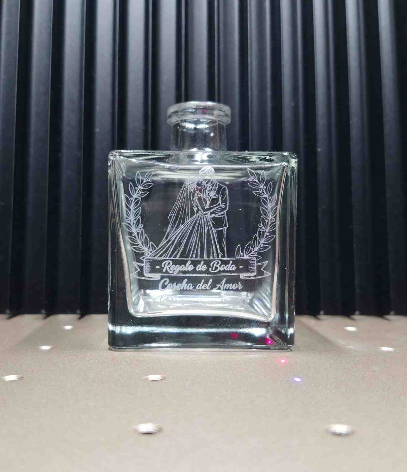 Botella de vidrio grabada con diseño y texto de pareja de novios.