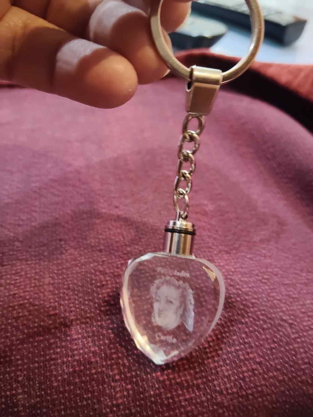 Persona sosteniendo un llavero de cristal en forma de corazón con un retrato grabado en el interior.