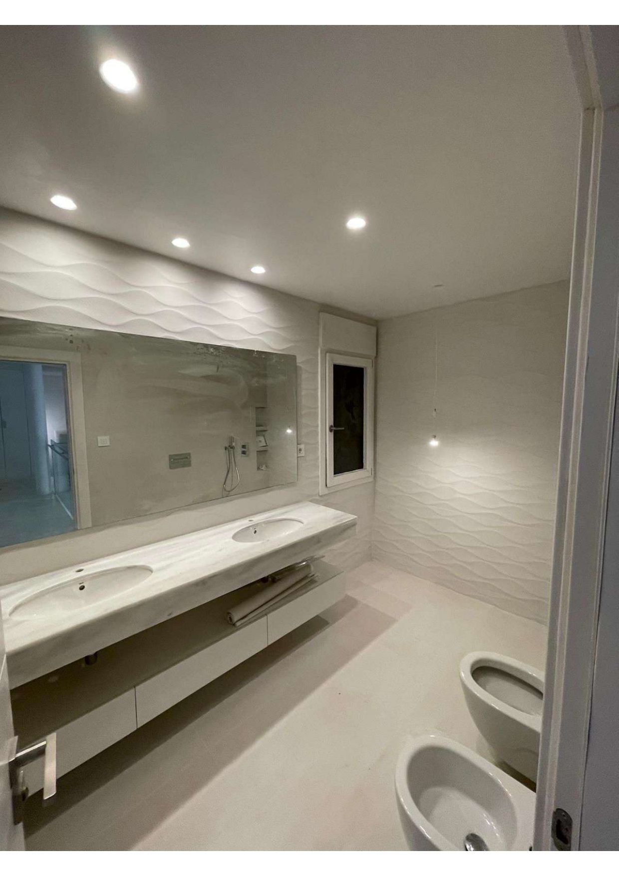 Un baño con dos lavabos, dos inodoros y un gran espejo.