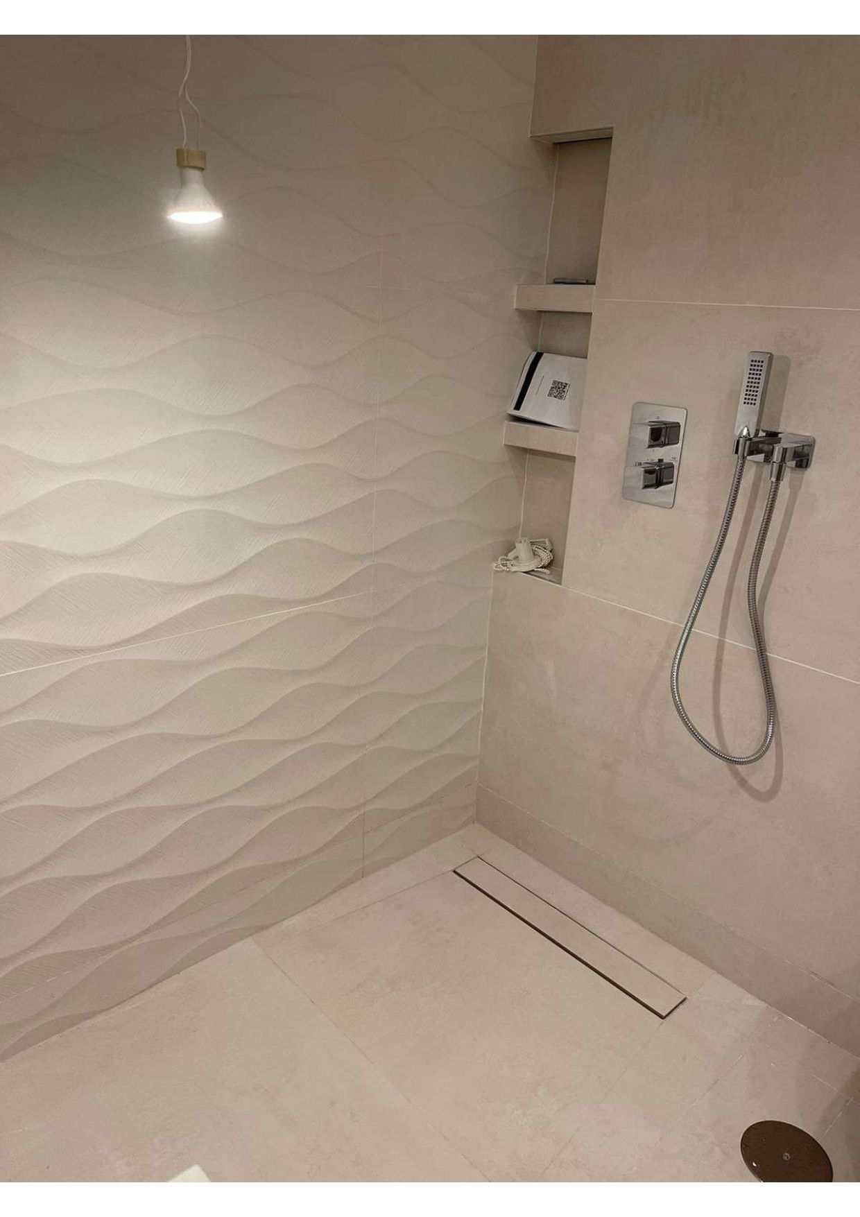 Un baño con ducha a ras de suelo y cabezal de ducha.