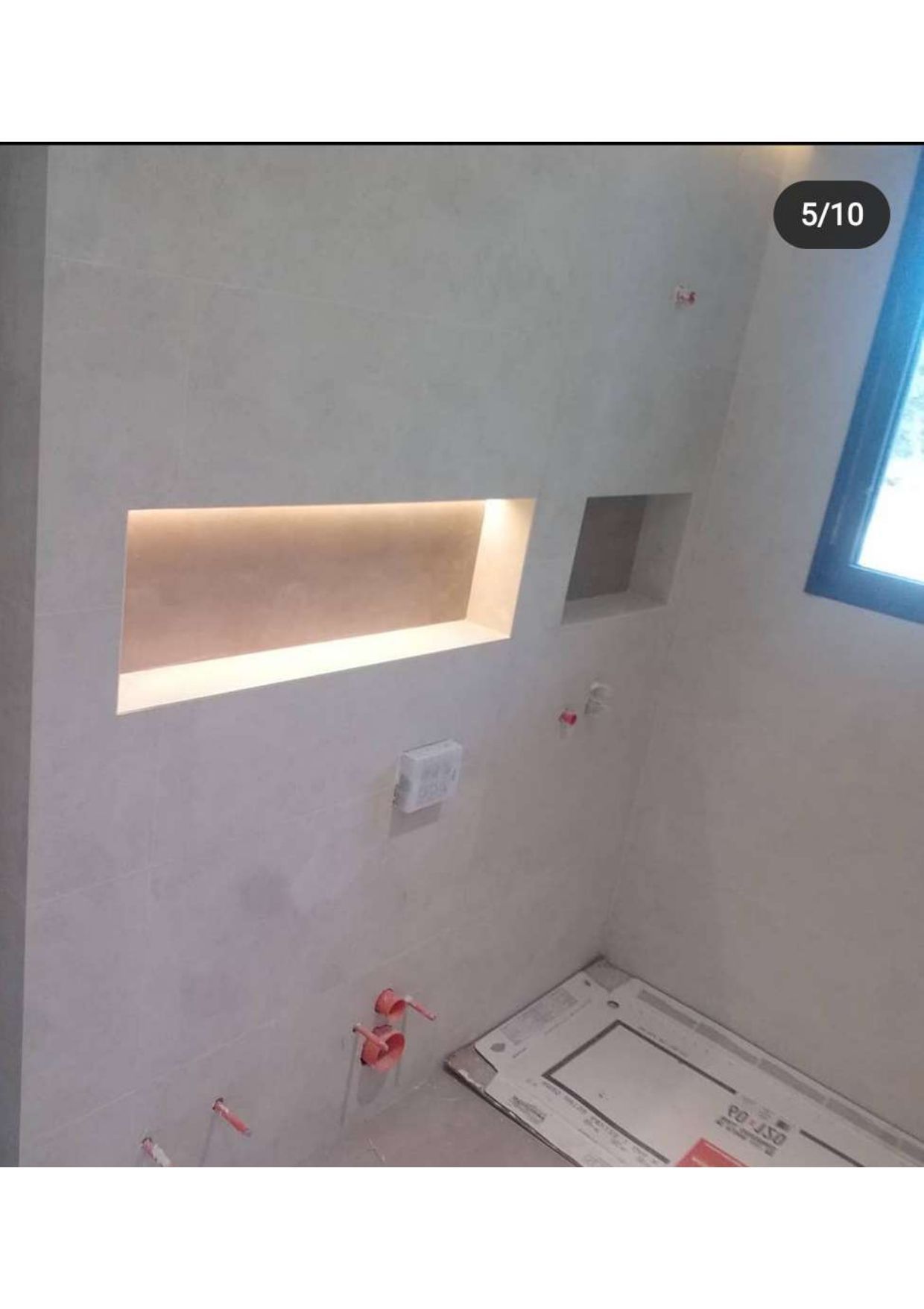 Un baño con una ventana y un estante en la pared.