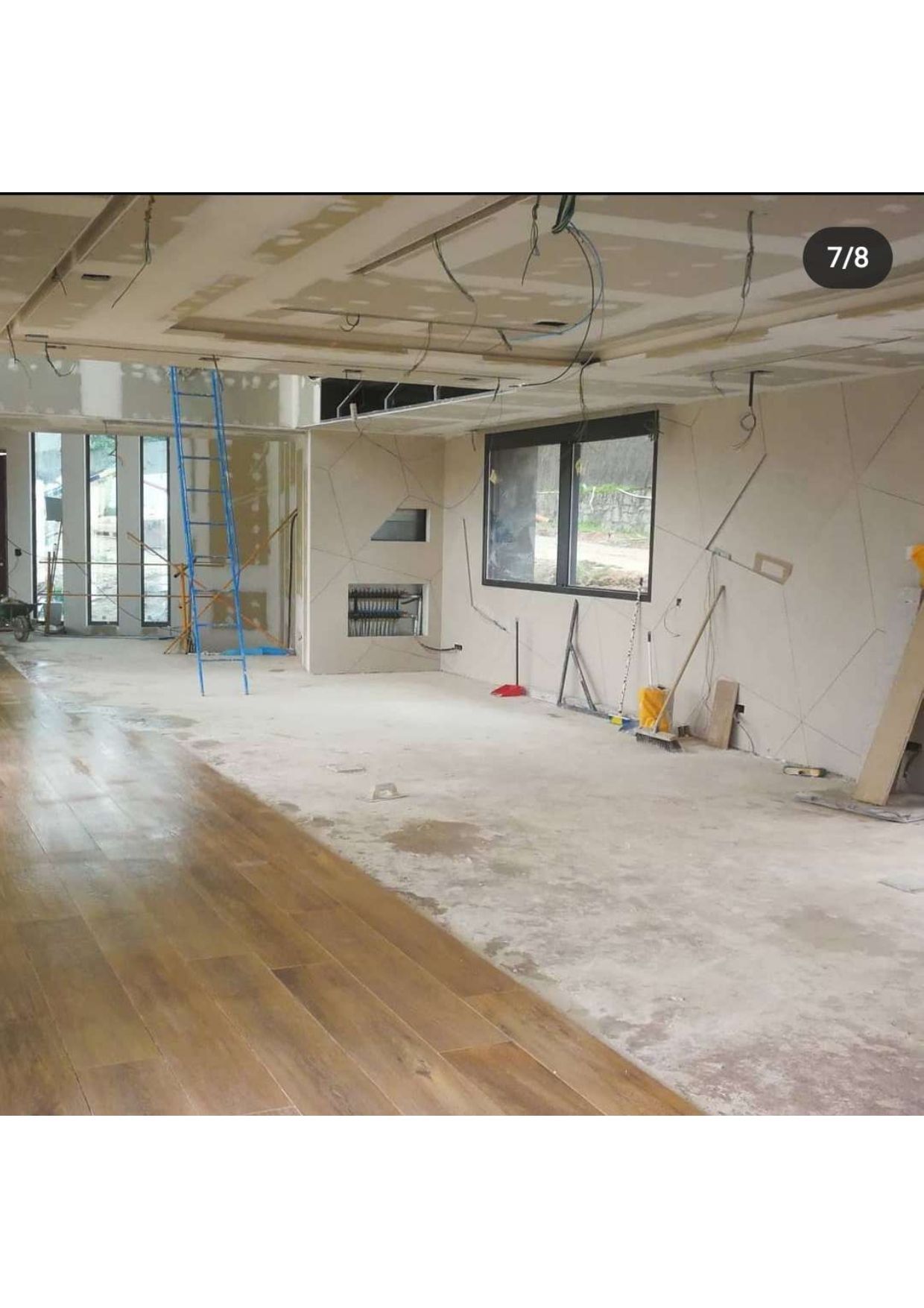 Una gran habitación vacía con suelos de madera y paredes blancas en construcción.
