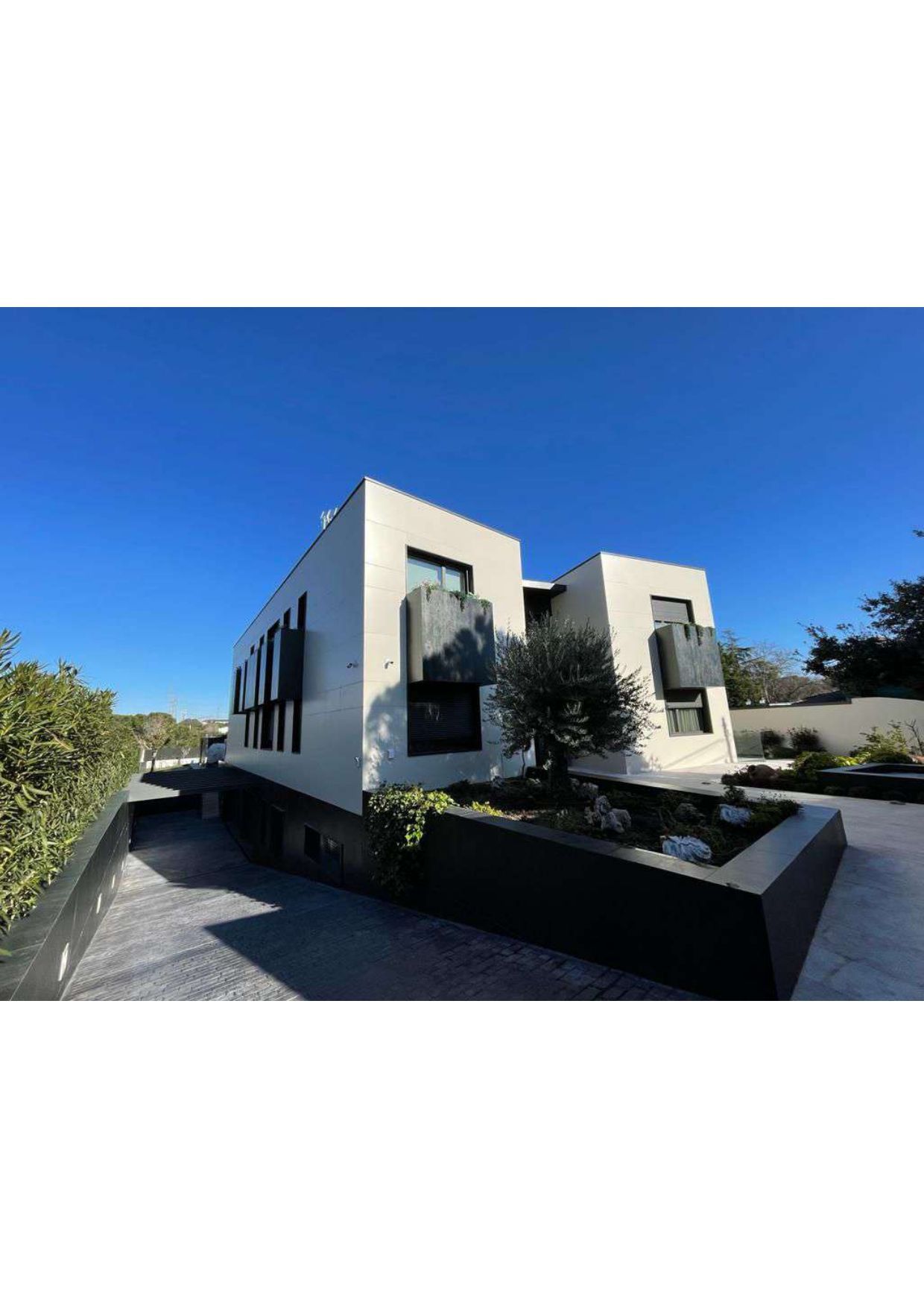 Una gran casa blanca con muchas ventanas y un camino de entrada que conduce a ella.