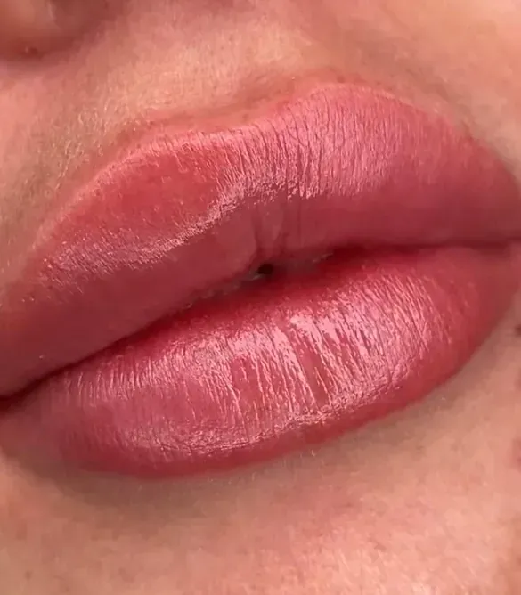 Un primer plano de los labios de una mujer con lápiz labial rosa.