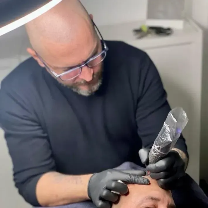 Un hombre se está haciendo un tatuaje en la frente de un hombre.