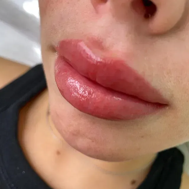 Un primer plano de los labios de una mujer con una camiseta sin mangas negra.